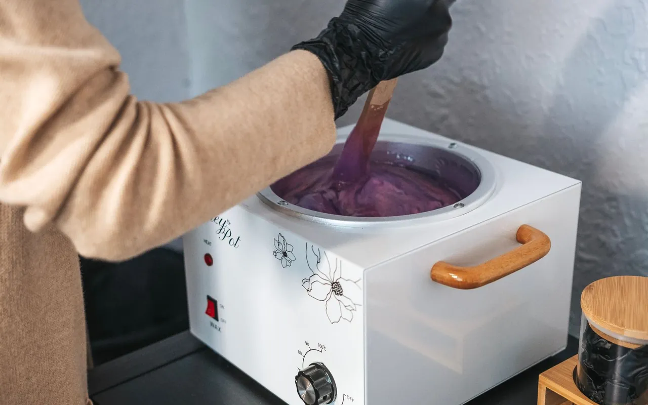 Beauty professional preparing warm wax in a salon wax heater